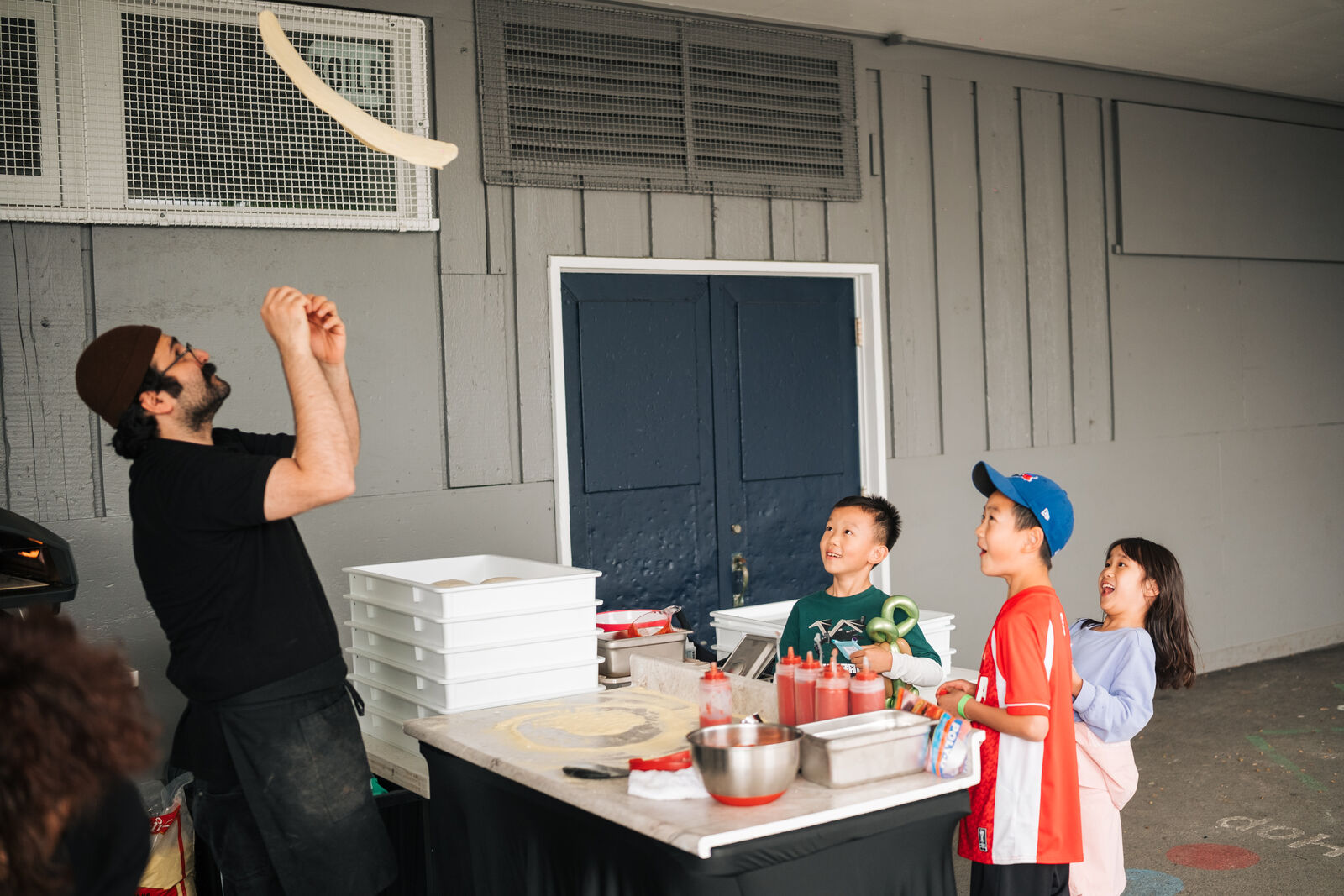 Chef showing a young guest how pizza dough is prepared at a school fair in West Vancouver
